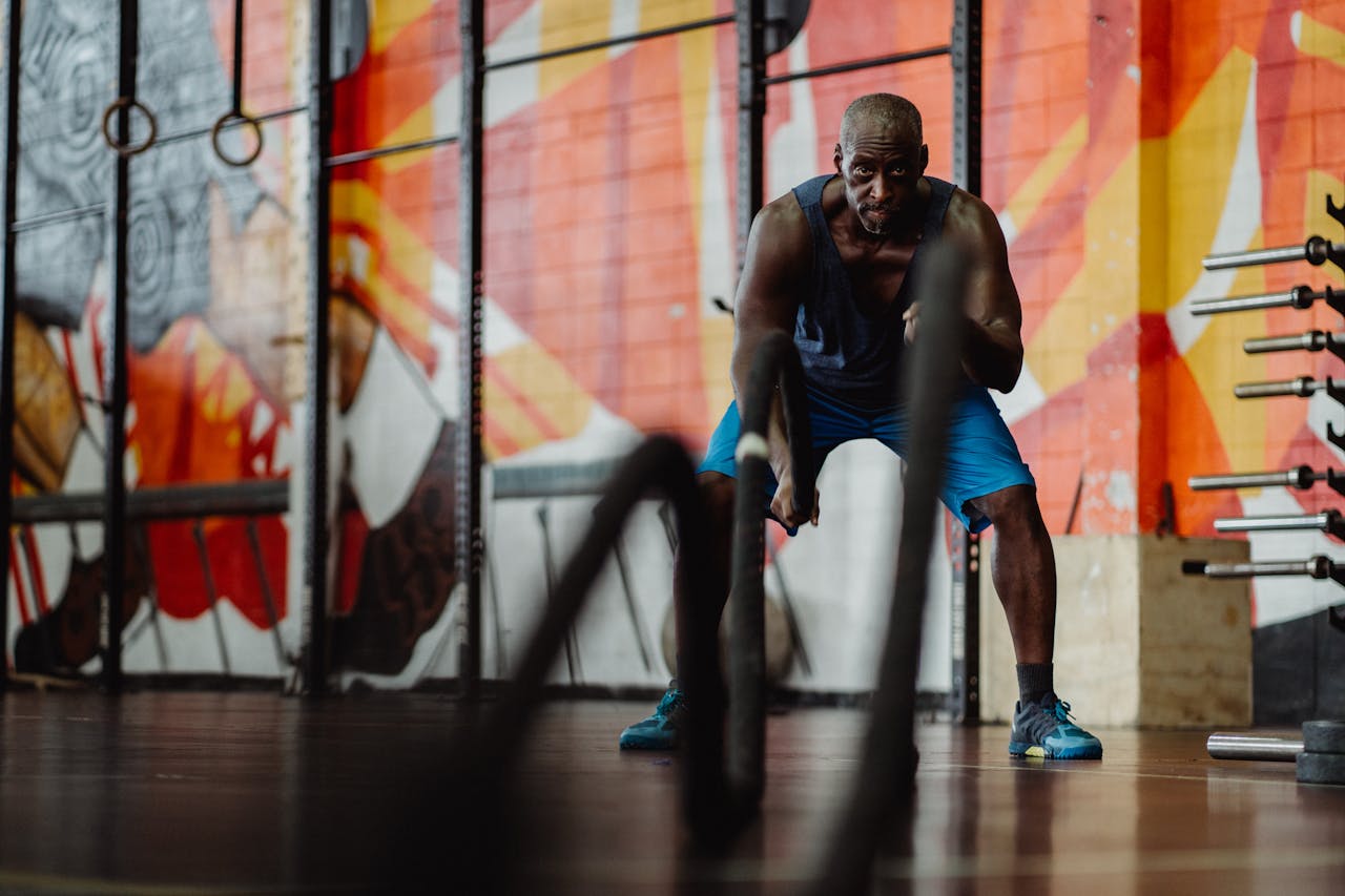 services-02 Athlete performing an intense workout with battle ropes in a vibrant gym setting.