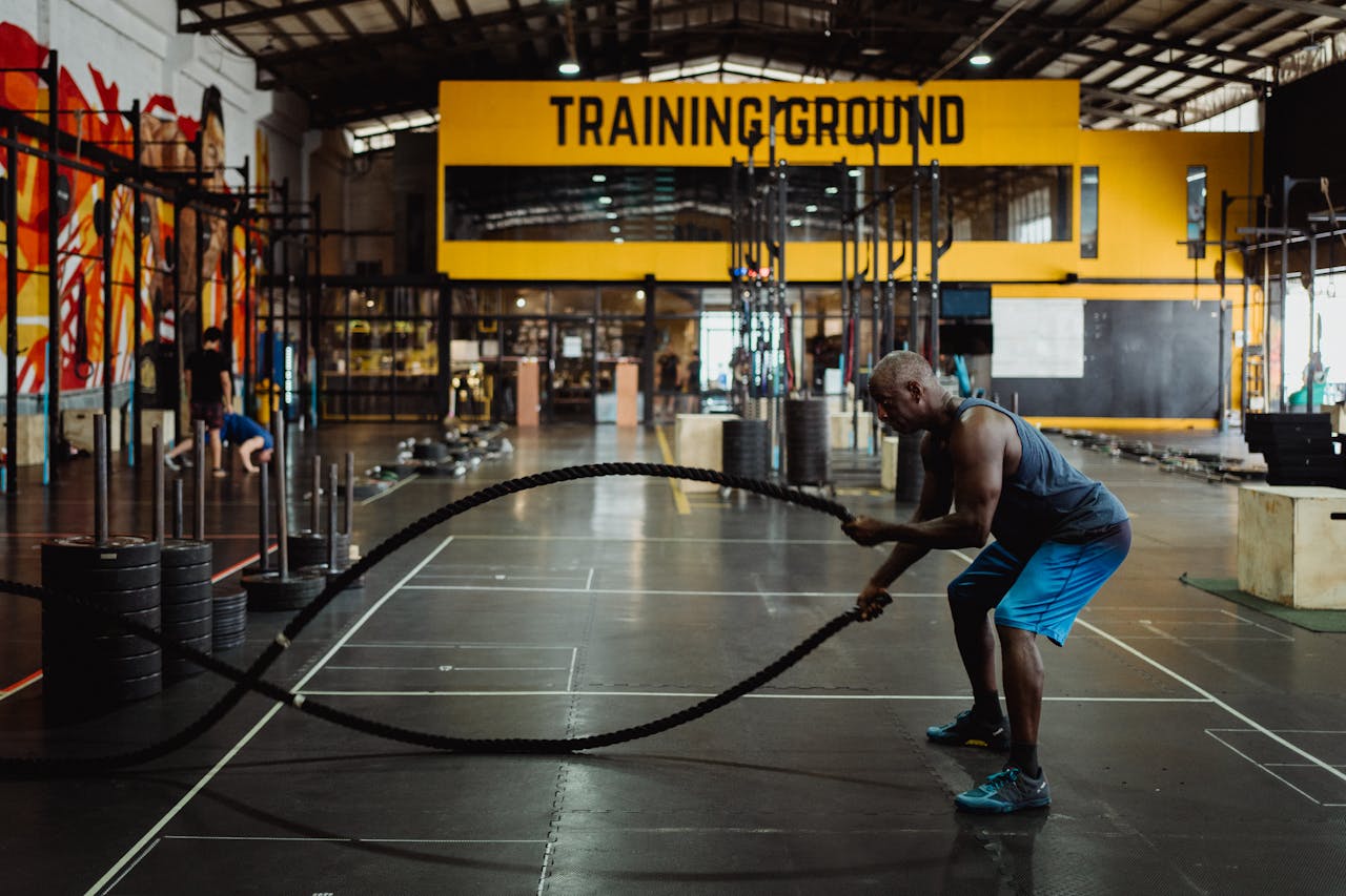 hero-img Athletic man engaging in a battle rope workout inside a modern gym setting for fitness training.